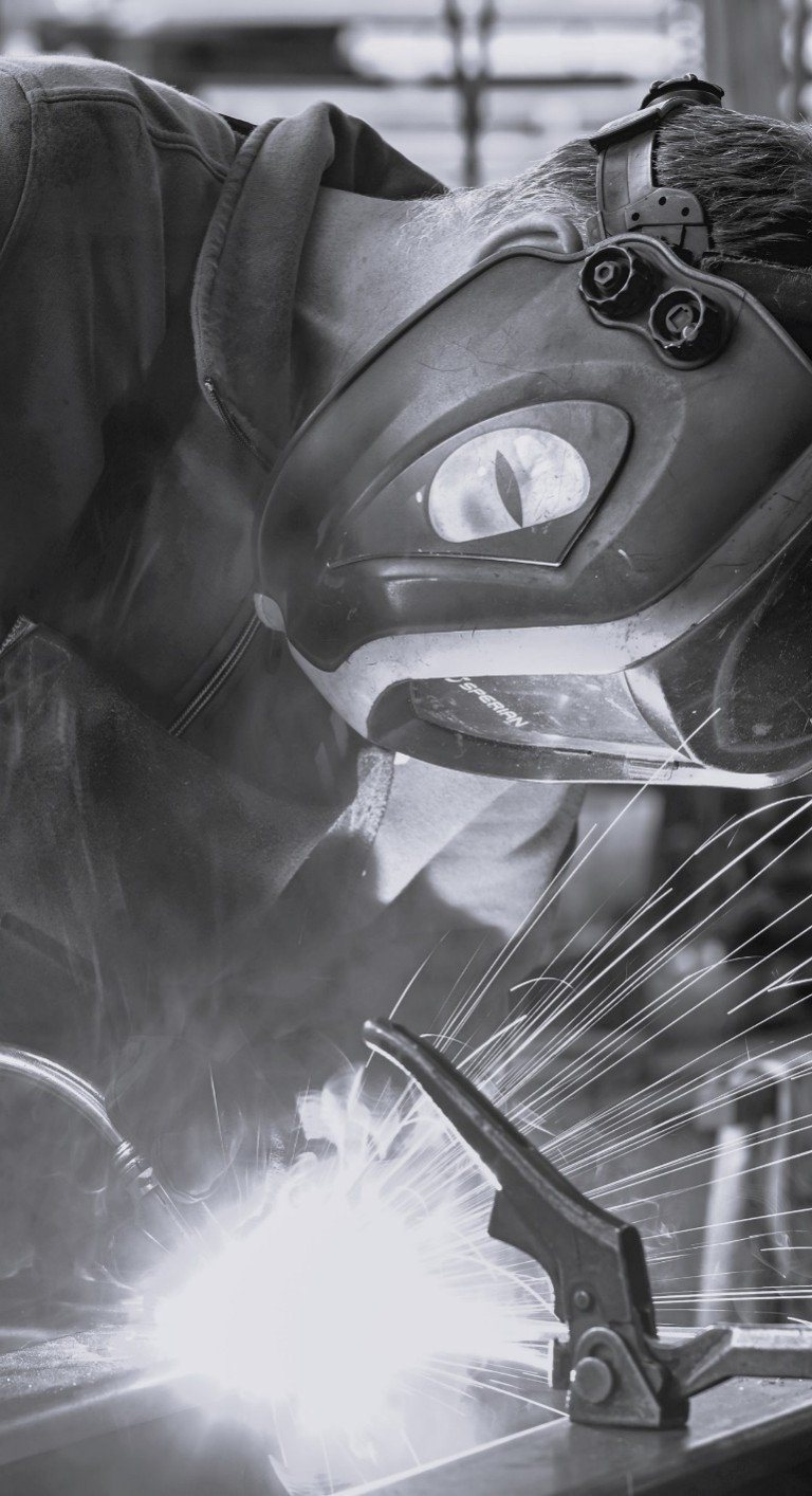 Certified welder on high-security construction Close-up of a welder working on a reinforced steel frame for a security system.