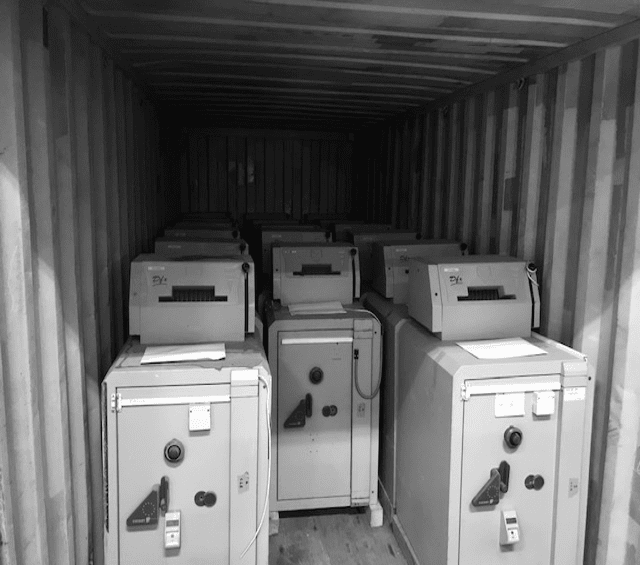Transportklare voorraad van beveiligde kluizen en koffers in een container voor grootschalige projecten.